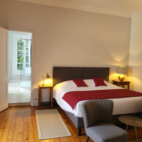 Chambre Chesnel aux Logis des Tourelles à Cognac avec lit queen-size, accents rouges, parquet et vue sur la ville