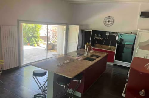 Modern kitchen with red island, wood countertop, and terrace access at La Conciergerie De Franck villa in Boissieres