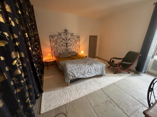 Elegant bedroom at La Conciergerie De Franck cottage in Boissieres with ornate metal headboard, ambient lighting, and sitting