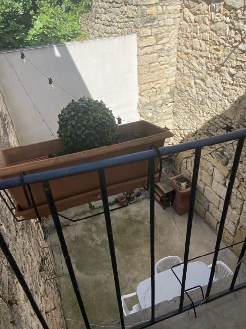 Balcony view of La Conciergerie De Franck cottage in Boissieres with potted plants and stone walls