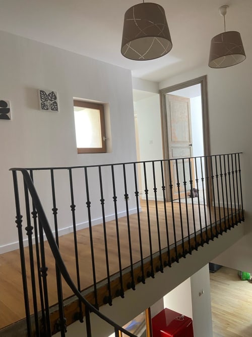 Modern loft-style landing with black metal railing, taupe pendant lights, and access to rooms at La Conciergerie De Franck