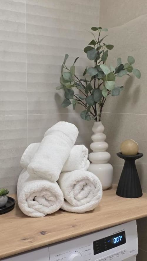 Baño estilo spa con toallas blancas enrolladas, eucalipto y artículos decorativos en MiramaRent Dream in the sea