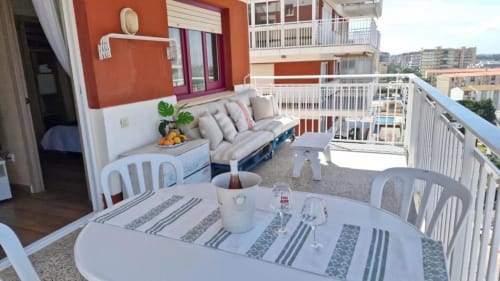 Apartamento con balcón en Benicàssim, mesa de comedor, sofá con vista al mar y horizonte de la ciudad