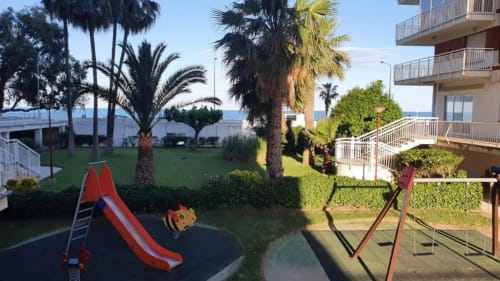 Parque infantil con tobogán rojo y equipamiento con vistas al mar en el apartamento MiramaRent de Benicàssim
