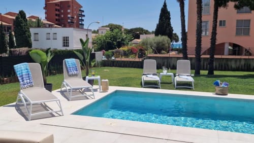Piscina y tumbonas en MiramaRent, Benicàssim. Patio soleado con césped verde y jardines mediterráneos.
