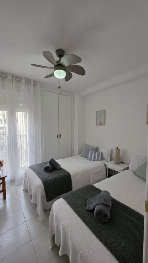 Dormitorio moderno en Regata Apartment de Benicàssim con camas gemelas, ventilador de techo, armario encalado y puertas balconeras