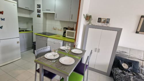 Cocina-comedor moderno en Apartamento Regata, Benicàssim con encimera verde lima, mesa de comedor preparada para tres