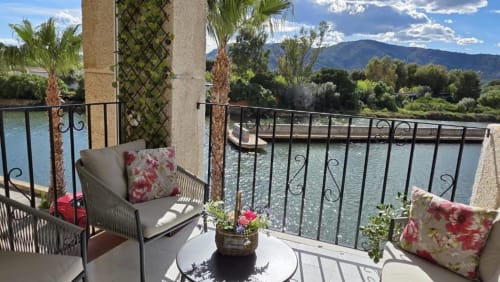 Balcón del apartamento Regata en Benicàssim con vistas al lago, mobiliario amueblado, plantas floridas y paisaje de montaña