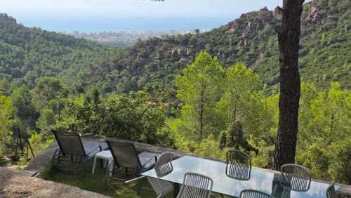 Terraza de villa en Benicàssim con mesa de comedor con vistas a valle boscoso y horizonte costero urbano