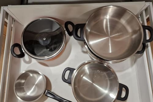 Juego de utensilios de cocina en acero inoxidable con tapas en el cajón de la cocina de la villa MiramaRent Benicàssim