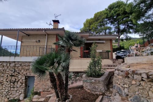 Villa en Benicàssim con terraza, muros de piedra, palmera y vistas a las montañas en parque natural