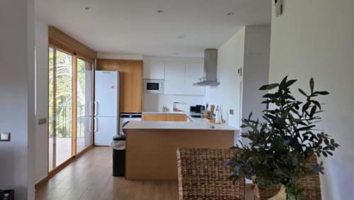 Cocina moderna con muebles de madera, encimeras blancas, isla central y acceso a terraza con vistas a Benicàssim