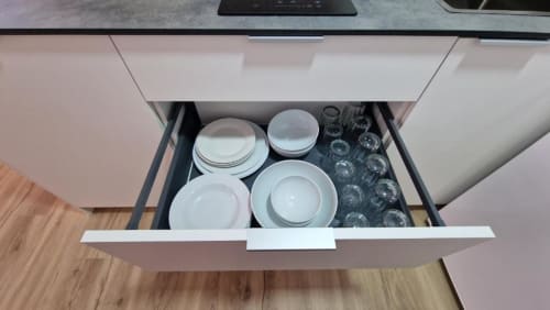 Cajón de cocina abierto mostrando vajilla blanca y cristalería del apartamento de playa MiramaRent, Benicàssim