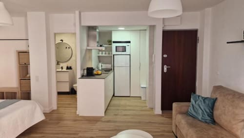 Estudio moderno en Benicàssim con cocina americana, sofá, cama y suelos de madera cerca de la playa