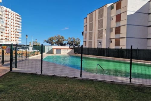 Piscina vallada con secciones coloridas en el complejo de apartamentos MiramaRent en Benicàssim, España, rodeada de viviendas residenciales