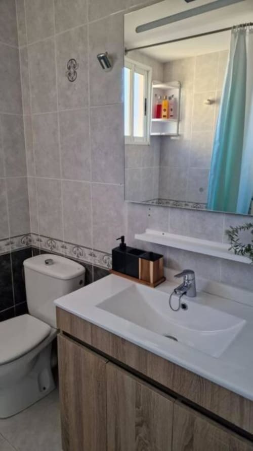 Baño moderno con vistas al mar en apartamento de MiramaRent, Benicàssim, con lavabo, inodoro, espejo y ducha