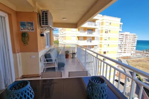 Balcón de apartamento con vistas al mar en Benicàssim, hamacas, aguas turquesas del Mediterráneo y edificios amarillos del resort