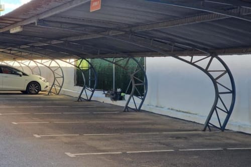 Cochera cubierta con muros blancos y estructura metálica en el apartamento MiramaRent de Benicàssim, con plaza de aparcamiento