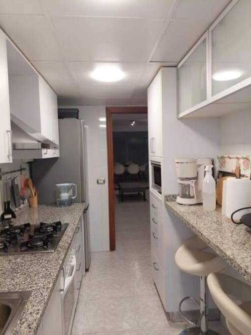 Cocina moderna con encimeras de granito, estufa de gas y gabinetes blancos en el apartamento MiramaRent en Benicàssim