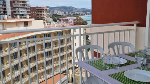 Balcón de apartamento en Benicàssim con vistas al mar y montañas, mesa de comedor, muebles de exterior frente a la costa mediterránea