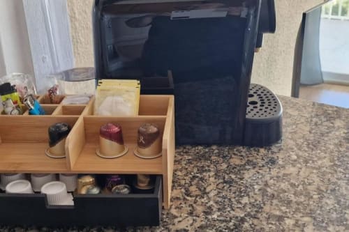 Estación de café con cápsulas y organizador sobre encimera de granito en el apartamento Sunset de MiramaRent, Benicàssim