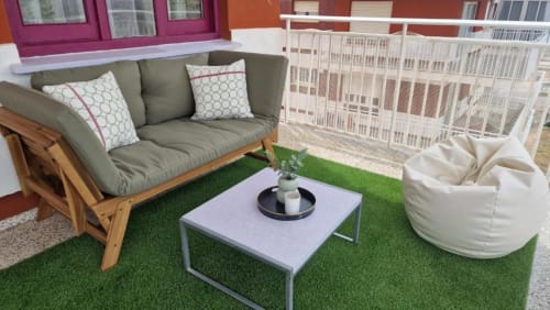 Terraza de apartamento en Benicàssim con sofá gris, puf blanco, mesita baja y césped artificial con vistas al mar
