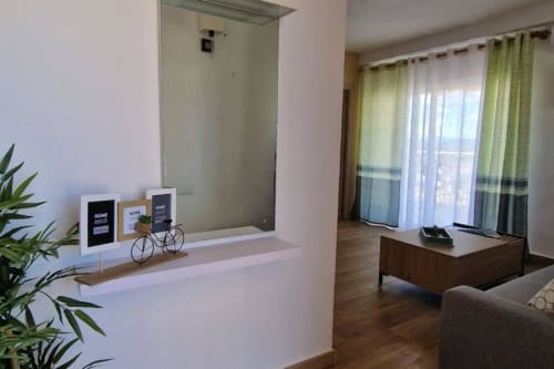 Sala de estar moderna en MiramaRent Benicàssim con vista al mar, amueblada con sofá, escritorio y cortinas verdes