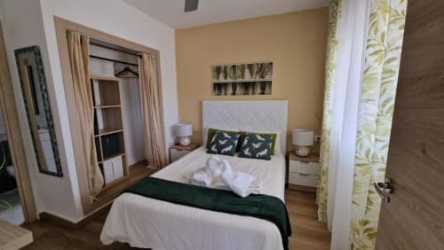 Dormitorio luminoso del apartamento MiramaRent Sunset en Benicàssim con cabecero blanco, detalles verdes y decoración con vistas al océano