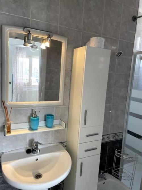 Baño moderno en apartamento Sunset de MiramaRent, Benicàssim con espejo iluminado, lavamanos blanco y paredes alicatadas