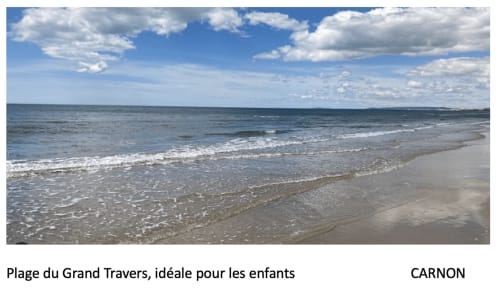 Sandy beach with gentle waves and blue sky, Grand Travers beach in Carnon, ideal for families