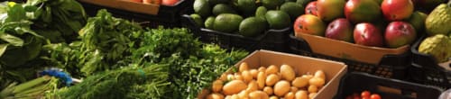 Fresh produce display at La Conciergerie De Franck: leafy greens, onions, apples, and avocados at the Boissieres market