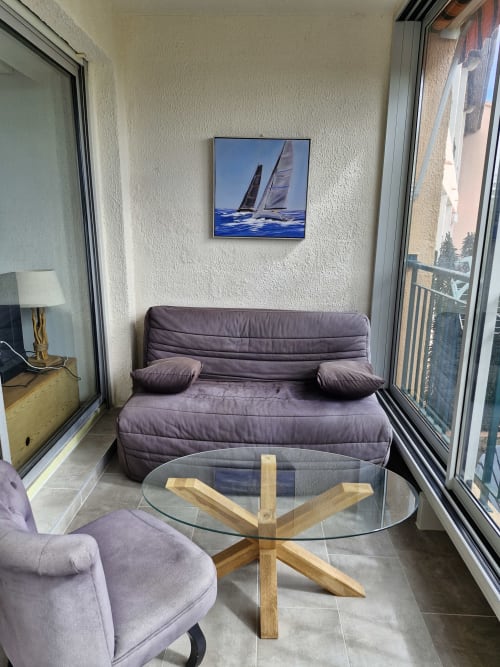 Séjour moderne avec canapé violet, table en verre et tableau de voiliers dominant Ajaccio, Corse