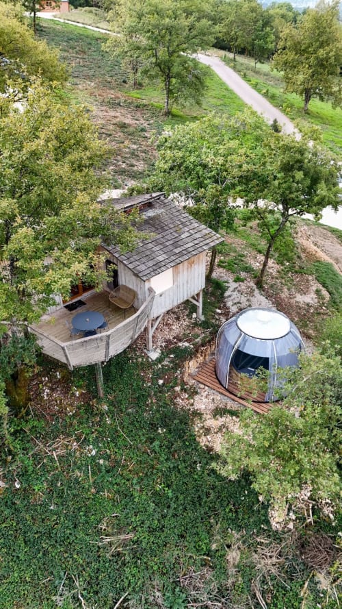 Aerial view of two modern glamping cabins nestled among trees with spa facilities at Cabanes et lodges du Belvédère in