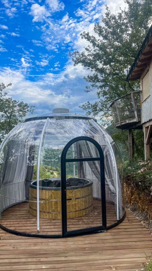 Dôme de glamping transparent avec bain à remous en bois sur la terrasse aux Cabanes et lodges du Belvédère, Serrières-sur-Ain