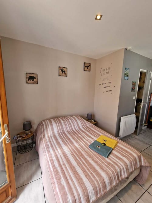 Chambre du studio Le Loup à Lamotte-Beuvron avec lit double, décoration murale nature et ambiance chaleureuse.