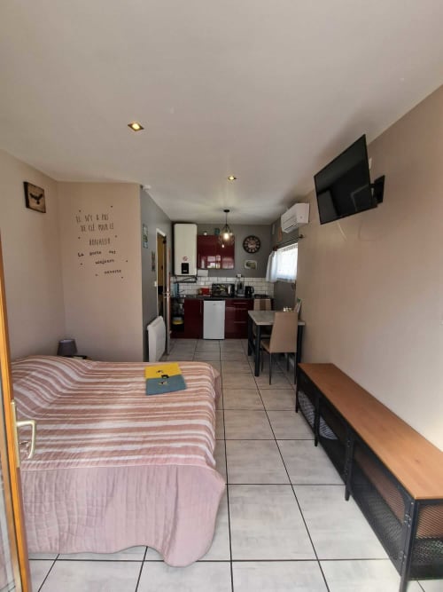 Intérieur du studio Le Loup à Lamotte-Beuvron avec lit double, climatisation, télévision murale, coin repas et kitchenette équipée, idéal pour un séjour confortable en Sologne.