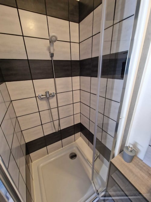 Douche carrelée du studio Le Loup à Lamotte-Beuvron avec paroi vitrée et pommeau réglable, salle d’eau moderne et pratique pour un séjour confortable en Sologne.