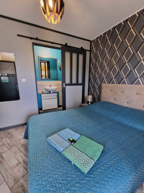 Chambre du studio Le Jardin, gîte Lamotte-Beuvron en Sologne, avec lit double, linge de maison coloré et accès direct à la salle de bain moderne.