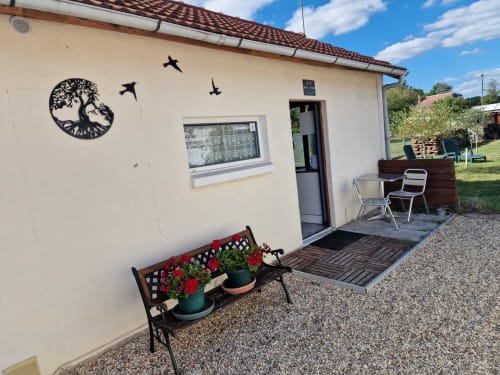 "Entrée du studio Le Jardin, gîte Lamotte-Beuvron en Sologne, avec banc fleuri, terrasse extérieure et coin repas convivial pour profiter d’un séjour agréable.