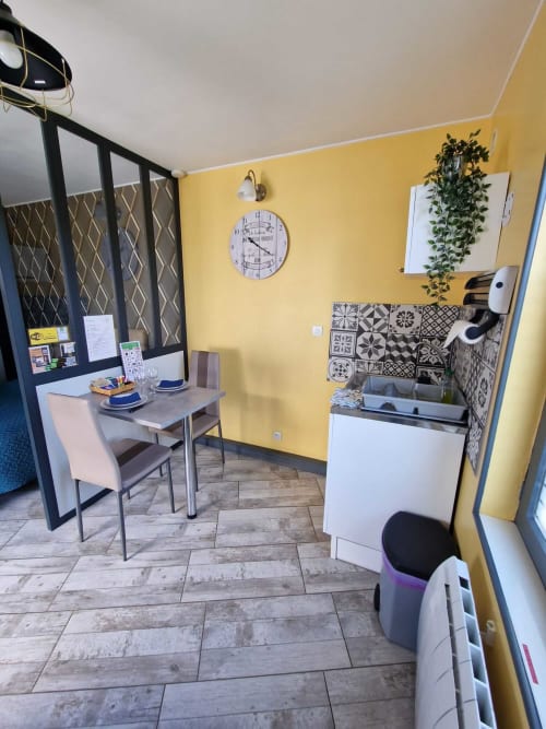 Espace repas et kitchenette du studio Le Jardin, gîte Lamotte-Beuvron en Sologne, avec table pour deux, coin cuisine équipé et décoration moderne pour un séjour confortable.
