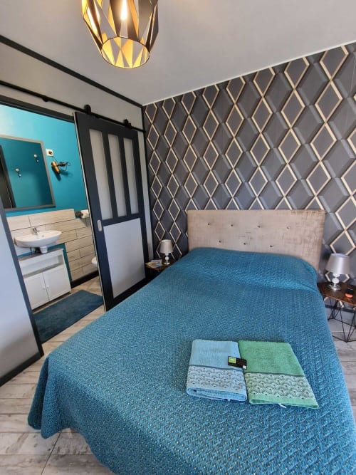 Chambre du studio Le Jardin, gîte Lamotte-Beuvron en Sologne, avec lit double, linge de maison fourni et accès direct à la salle de bain, offrant confort et décoration moderne.