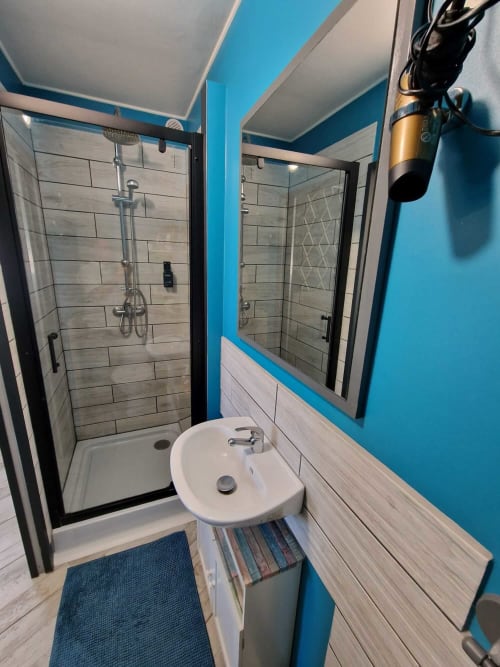 Salle de bain moderne du studio Le Jardin, gîte Lamotte-Beuvron en Sologne, avec douche carrelée, vasque, miroir et sèche-cheveux pour un séjour confortable.