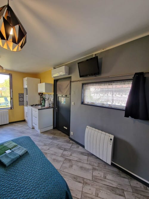 Intérieur du studio Le Jardin, gîte Lamotte-Beuvron en Sologne, avec lit double, télévision murale, climatisation et kitchenette équipée pour un séjour confortable.