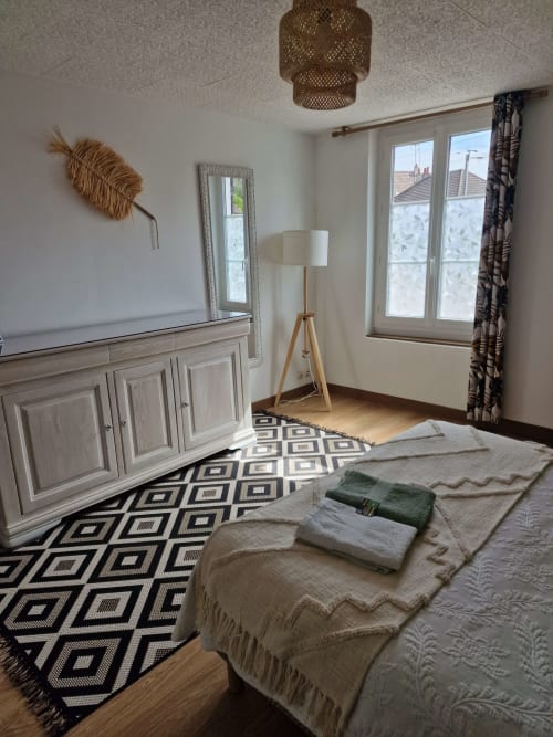 Chambre du gîte Harmonie à Lamotte-Beuvron avec commode en bois clair, décoration murale naturelle et tapis design, idéale pour un séjour chaleureux en Sologne.
