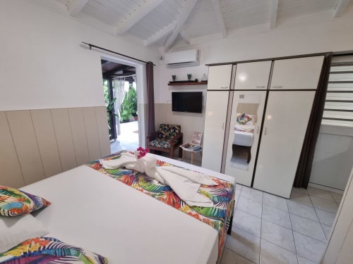 Studio bedroom at Gites Kaladja in Port-Louis with double bed, TV, wardrobe, and outdoor patio access