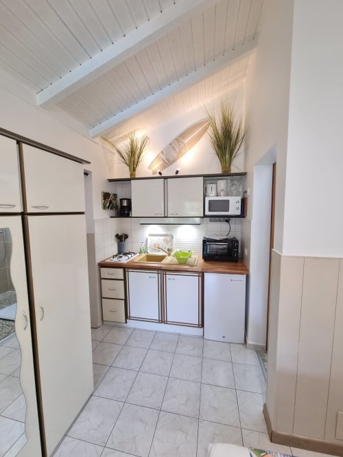 Modern kitchenette in Padjambel studio at Gites Kaladja, Port-Louis, with wooden countertop, white appliances, and sloped
