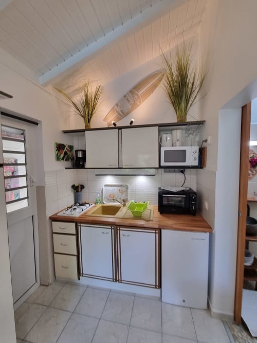 Compact kitchenette at Gites Kaladja in Port-Louis with cooking plate, microwave, refrigerator and white cabinets