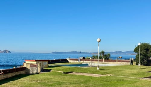 Jardín frente al mar de Holibai con piscina, terraza y vistas al mar sobre la costa de Baiona, España