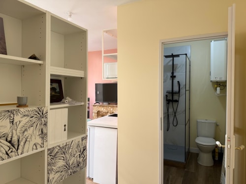 Gemütliches Studio-Badezimmer in Lourdes mit Dusche, Toilette, gelben Wänden und modernen schwarzen Armaturen