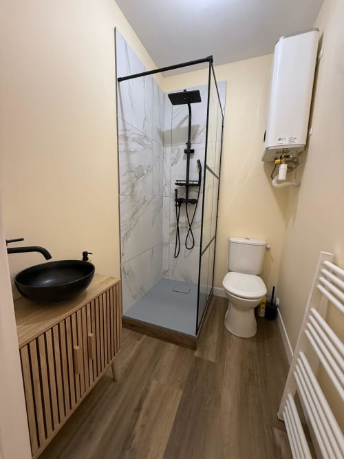 Modernes Badezimmer im Studio Lourdes mit Dusche, schwarzem Waschbecken, Toilette und weißem Warmwasserspeicher